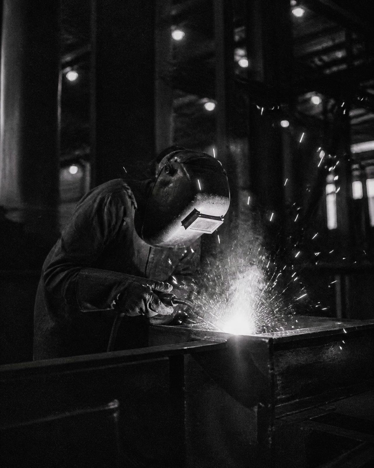 Welder working at night in a dim factory